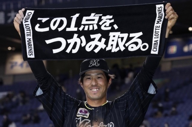 チームスローガンの入ったタオルを掲げるロッテ・岡大海 (C) Kyodo News