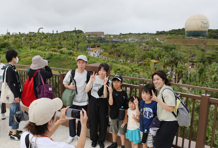 開業したテーマパーク「JUNGLIA OKINAWA(ジャングリア沖縄)」で記念撮影する人たち=25日午前、沖縄県今帰仁村