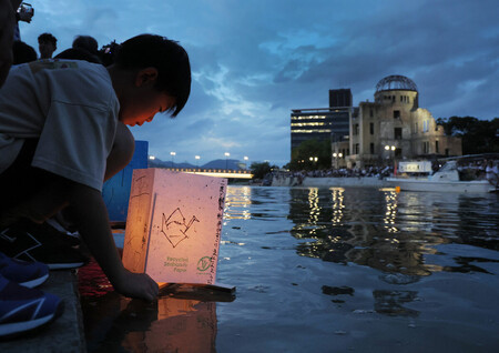原爆ドーム前の元安川に灯籠を流す人=6日午後、広島市中区
