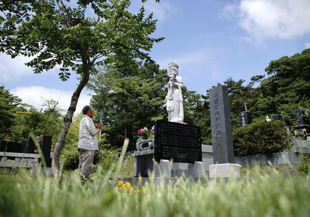 満蒙開拓団の供養塔に手を合わせる市川渥夫さん。今年6月、市川さんは慰霊のため団員2世らと中国の地を踏んだ。「若い人たちに開拓の記憶を伝えたかった」=7月22日、長野県軽井沢町の大日向開拓地