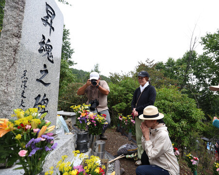 日航ジャンボ機墜落事故現場の「昇魂之碑」の前で手を合わせる俳優の黒木瞳さん(右端)=12日午前、群馬県上野村