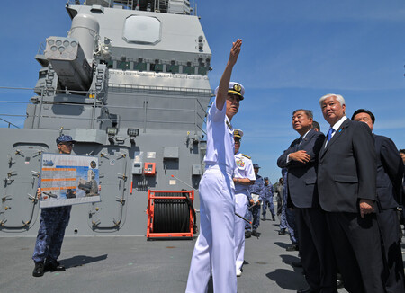 海上自衛隊の護衛艦「かが」を視察し、飛行甲板でSeaRAM(対艦ミサイル防御装置、左上)について竹内周作艦長(中央)から説明を受ける石破茂首相(右から2人目)、中谷元防衛相(右端)=23日午前、神奈川県横須賀市の海上自衛隊横須賀基地(代表撮影)