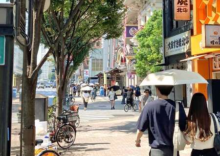 30日午後、強い日差しの下で東京・銀座の歌舞伎座近くを歩く人たち