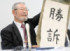 ふるさと納税訴訟の差し戻し審判決後の記者会見で、「勝訴」と書かれた紙を掲げ、笑顔を見せる原告側代理人の阿部泰隆弁護士＝９日午後、大阪市北区