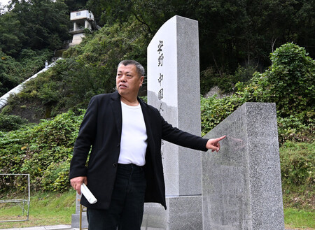 追悼式に先立ち、碑に刻まれた父・孟昭恩さんの名を指す憲法さん=19日午前、広島県安芸太田町