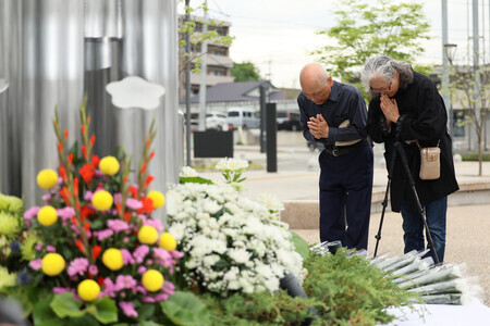 熊本地震の前震から10年がたち、献花台で手を合わせる古田学さん(左)と妻の妙さん。自宅が全壊したという=14日午前、熊本県益城町