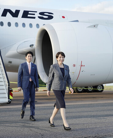 ロンドン郊外の空港に到着した高市早苗首相(右)。左は佐藤啓官房副長官=13日