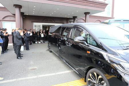 イオンモール熊本の爆発事故で亡くなった大竹玖瑠美さんのひつぎを乗せ、葬儀場を出る霊きゅう車=3日午後、熊本市西区