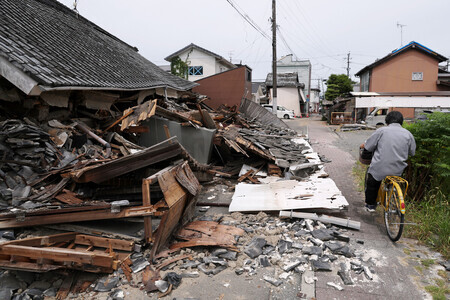 地震で倒壊し、道路をふさぐ建物=10日午前、熊本県八代市